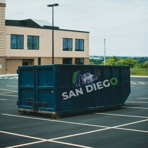An empty parking lot with a dumpster displaying a dumpster truck logo.